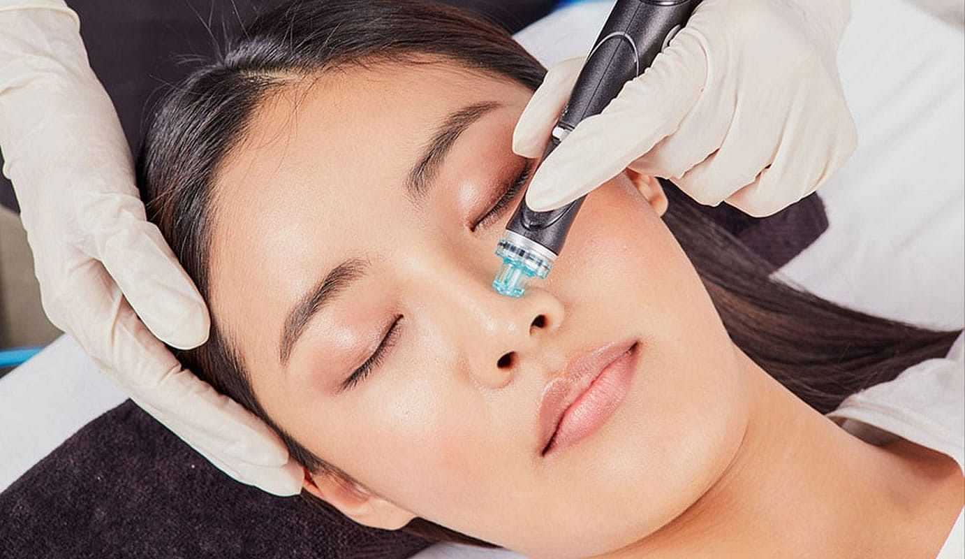 Person receiving a facial treatment with a skincare device, eyes closed and relaxed.