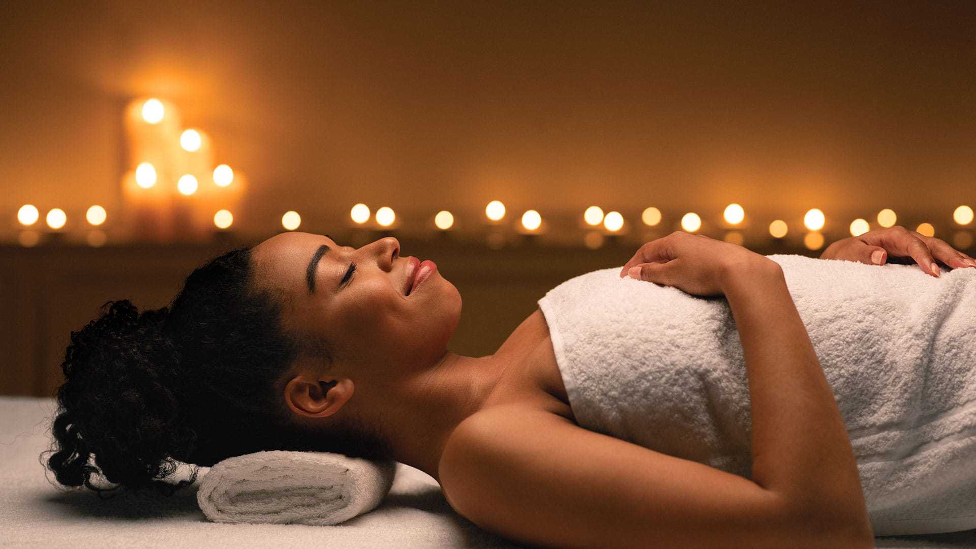 Woman relaxing at a spa with ambient candle lighting.