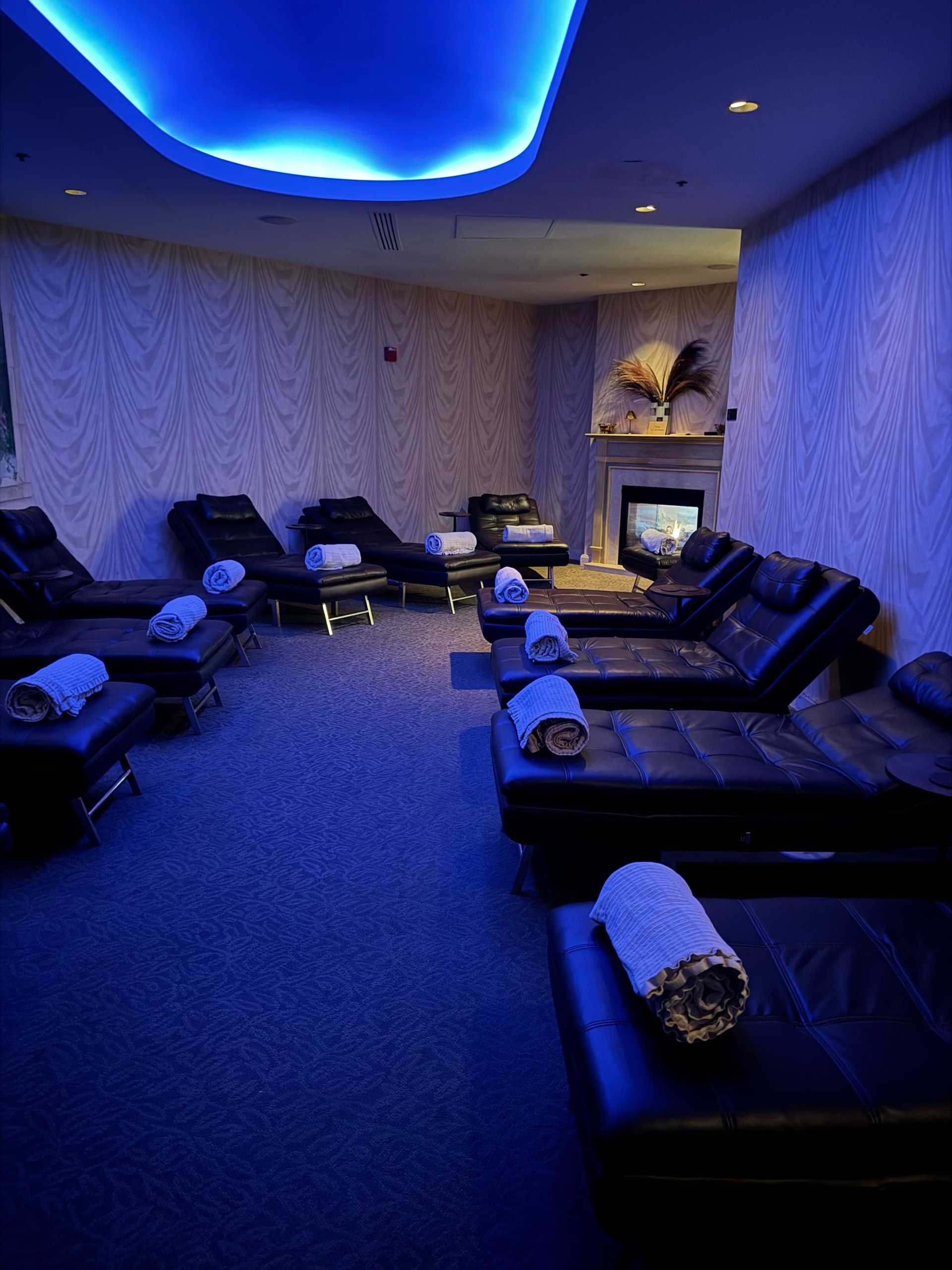 Luxurious spa lounge with leather chairs, soft lighting, and rolled towels.