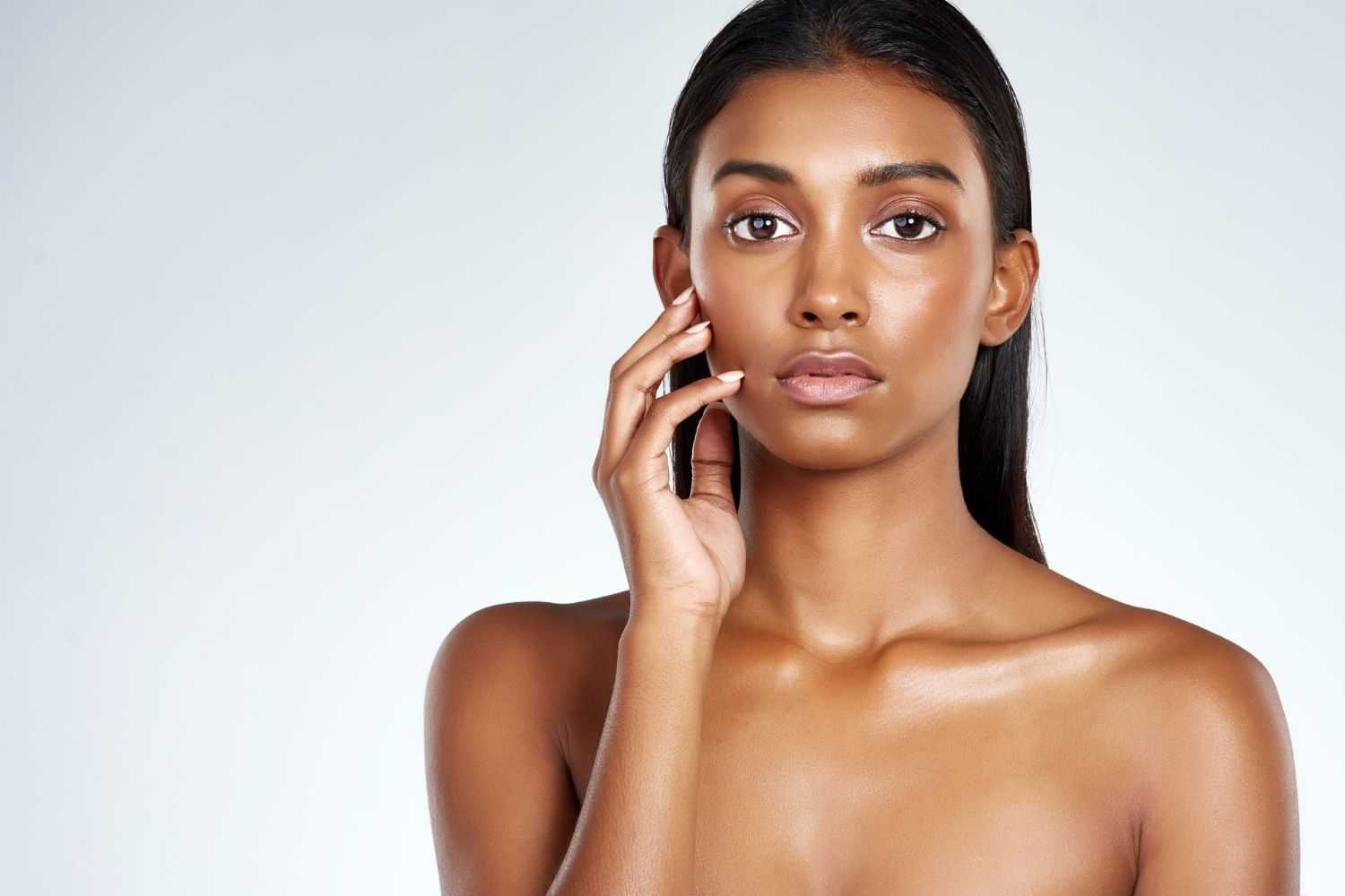 Woman with a serene expression touching her face.