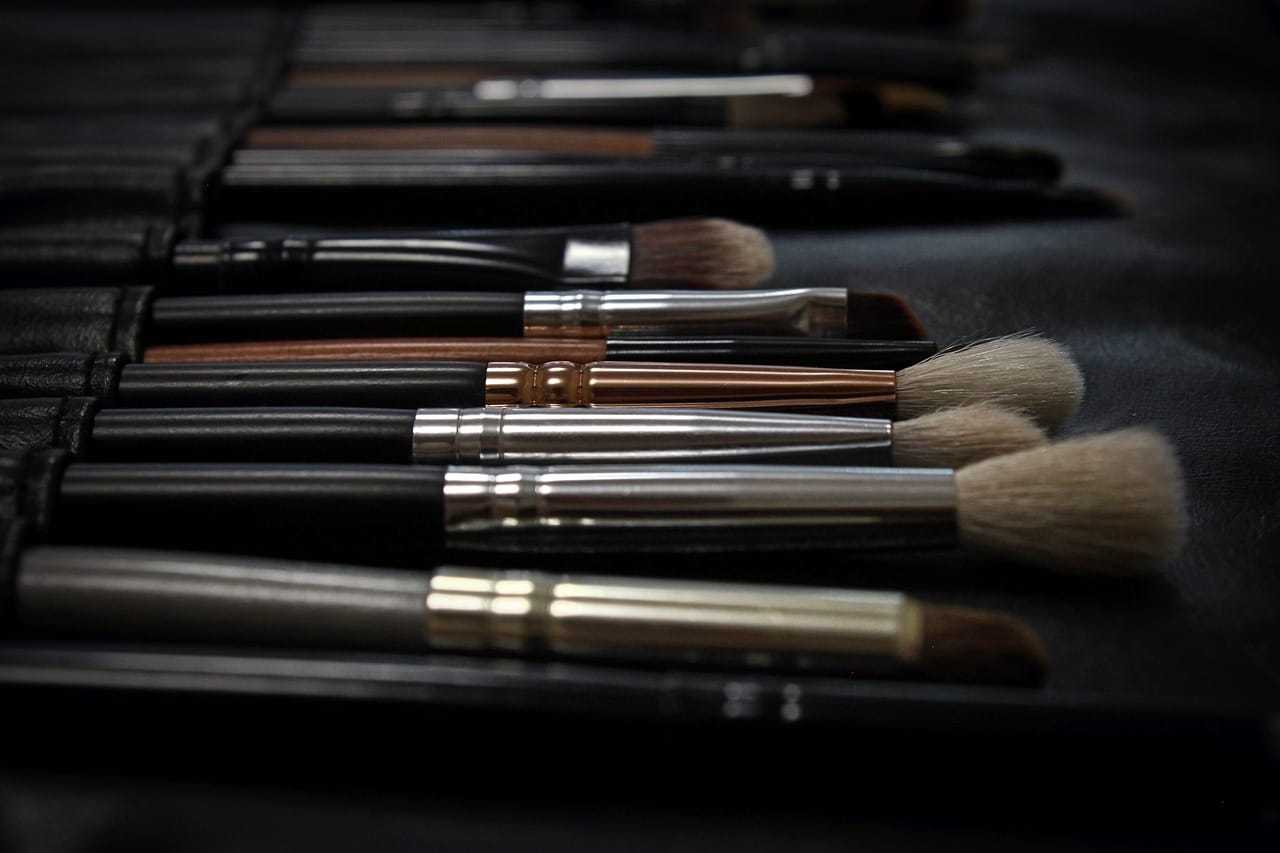 Makeup brushes neatly arranged on a black surface, varying in size and bristle type.