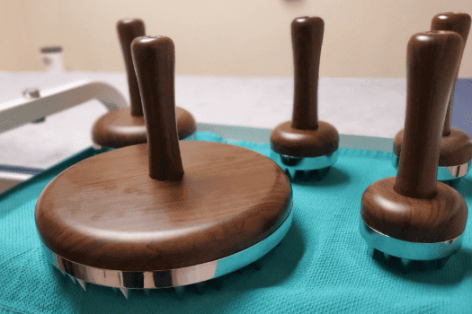 Wooden massage tools with metal accents on a teal mat.