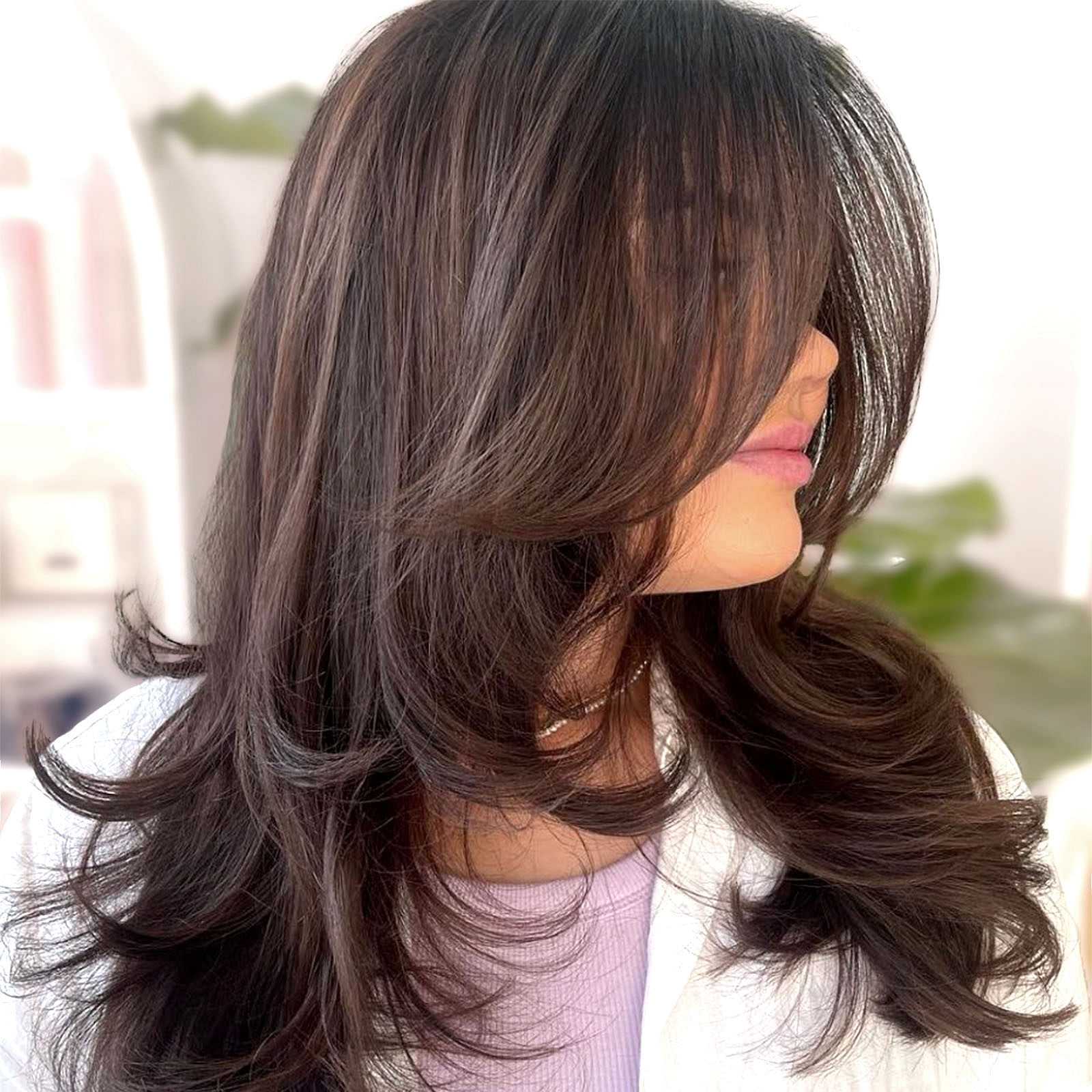 Woman with layered dark brown hair covering her face.