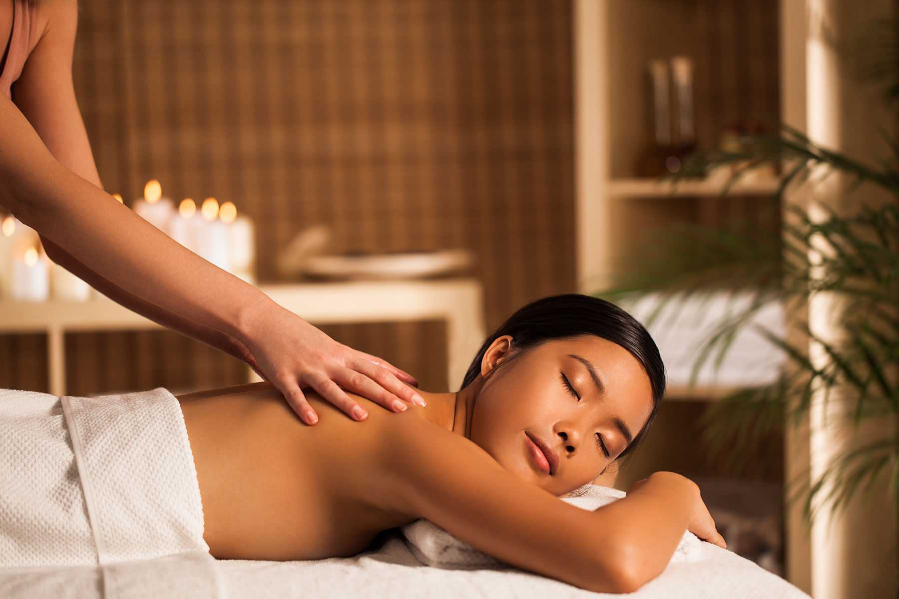 Woman receiving a back massage at a tranquil spa.