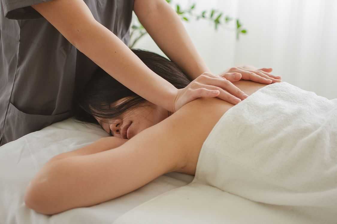 Person receiving a back massage in a tranquil setting.