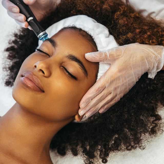Person receiving a facial treatment with a skincare device at a spa, eyes closed and relaxed.