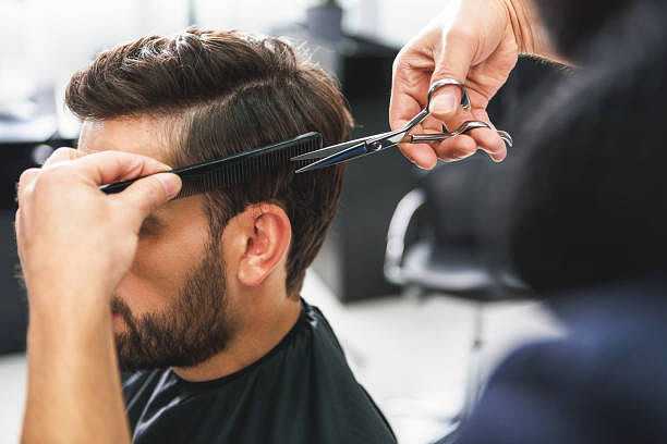 Man getting a haircut with scissors and comb at a salon.