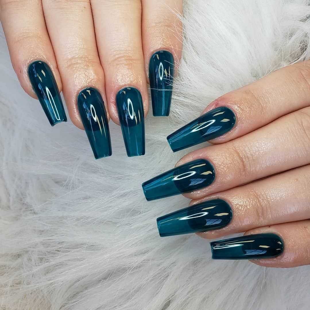 Hands with glossy, dark teal coffin-shaped nails on a white, furry surface.