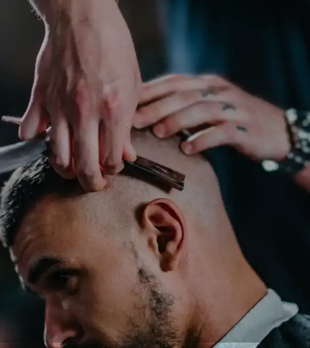 Barber shaving man's head with straight razor in close-up shot.