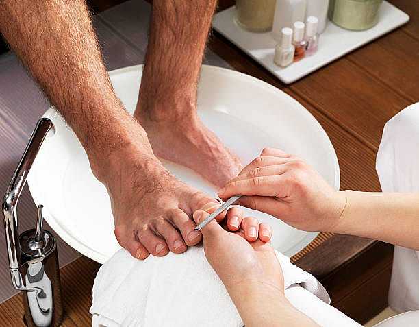 Man receiving a foot soak and nail care treatment in a spa setting.