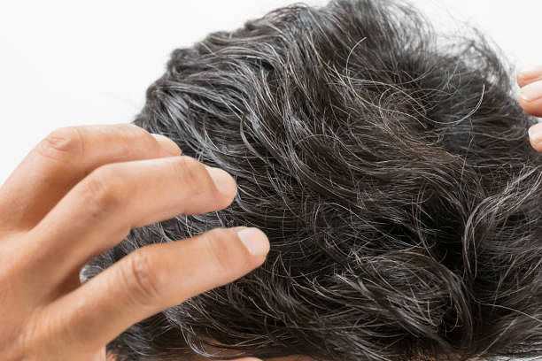 Person examining their thick, graying hair closely.
