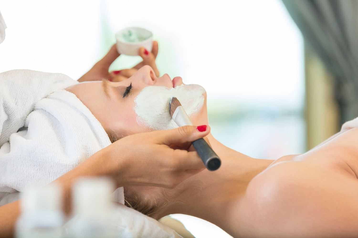 Woman receiving a facial mask treatment at a spa.