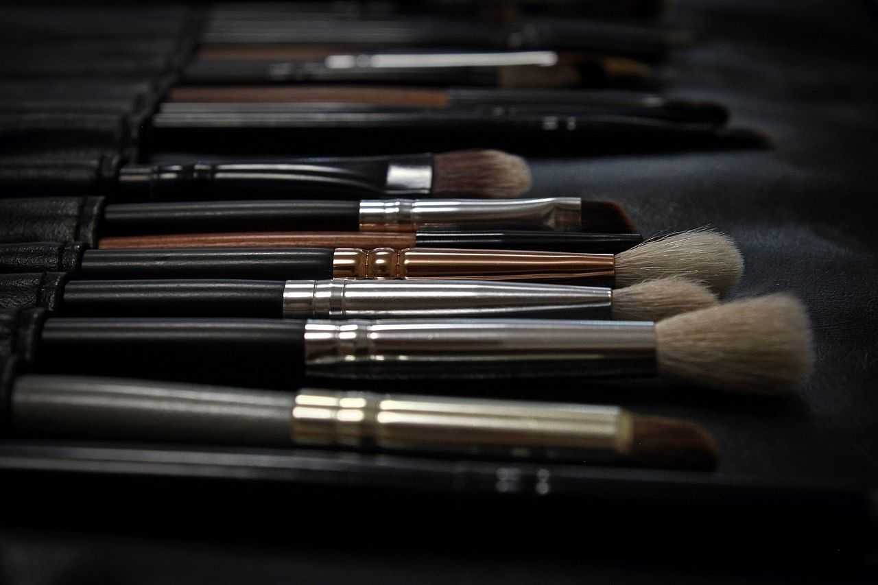 Makeup brushes neatly arranged on a black surface, varying in size and bristle type.