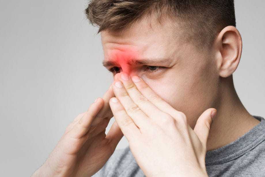 Man touching nose with red mark indicating sinus pain.
