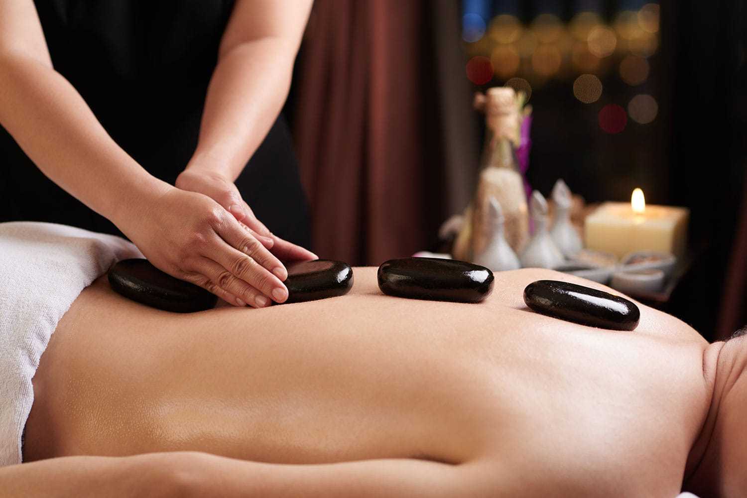 A person receiving a hot stone massage at a spa.