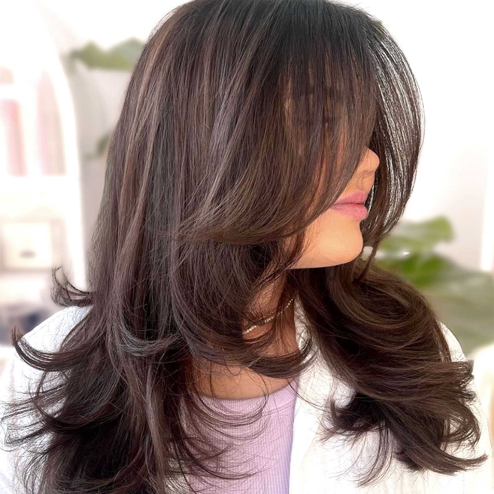 Woman with layered dark brown hair covering her face.