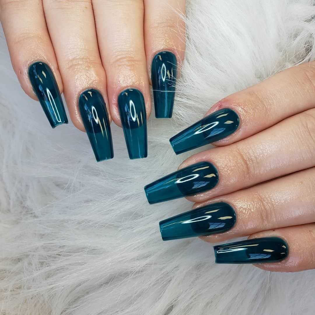 Hands with glossy, dark teal coffin-shaped nails on a white, furry surface.