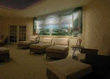 A dimly lit room with white sofas and a large window showing a scenic view.