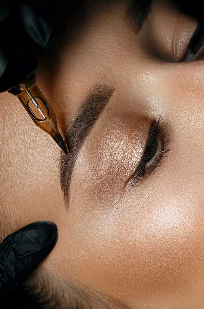 Close up of an eyebrow being shaped with a cosmetic pencil.